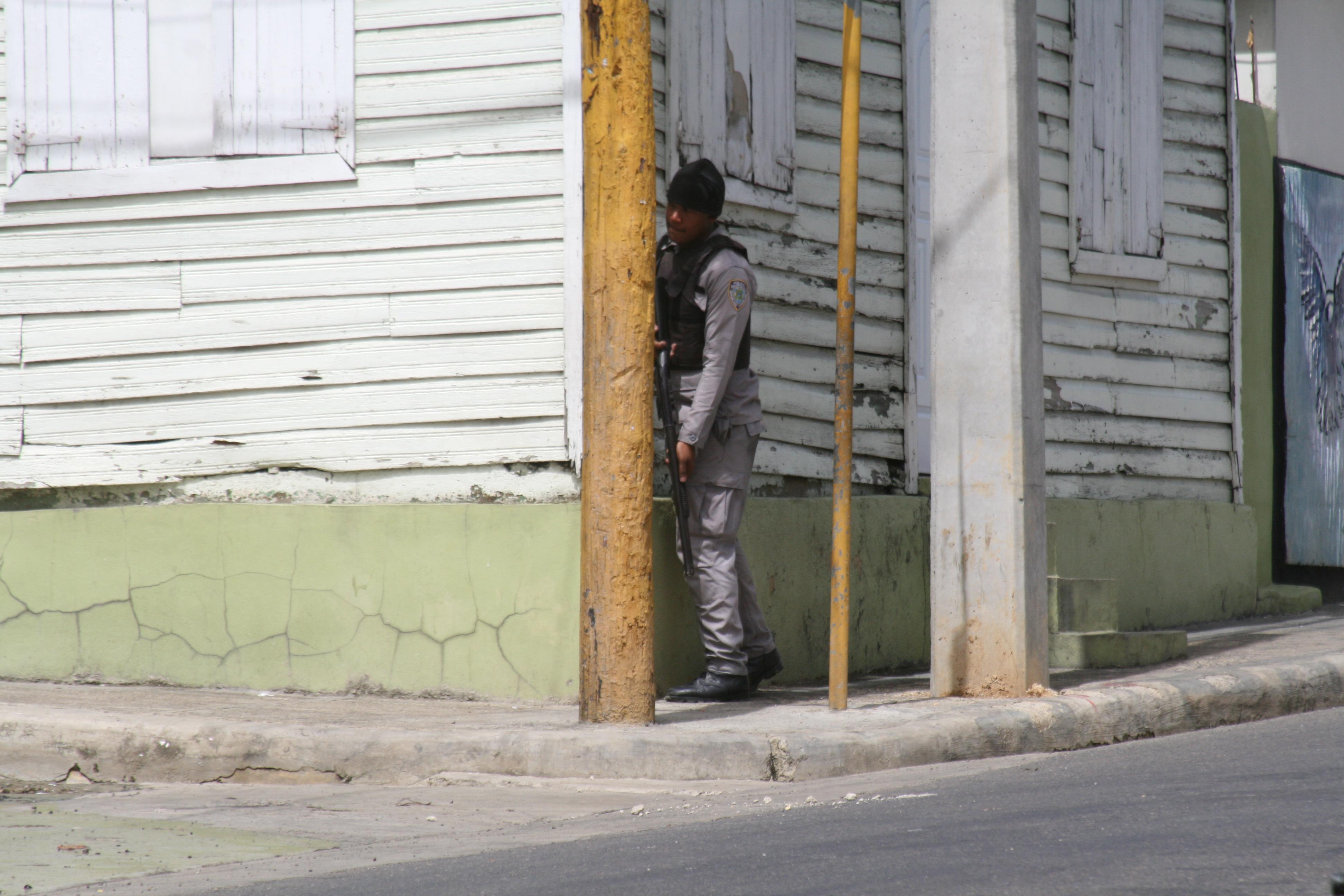 Un agente policial se protege de no ser alcanzado por una bala en medio de las protestas escenificadas durante el primer día de huelga en Salcedo. Foto David Rodríguez.