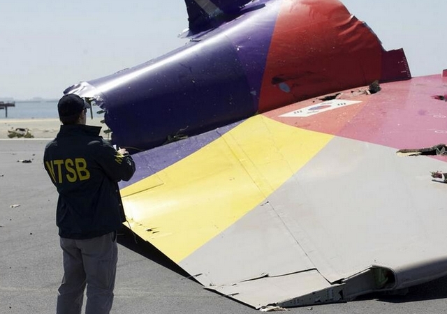 Un empleado de la Junta Nacional de Seguridad en el Transporte (NTSB), toma fotografías de las partes del avión esparcidas en la pista del aeropuerto de San Francisco.