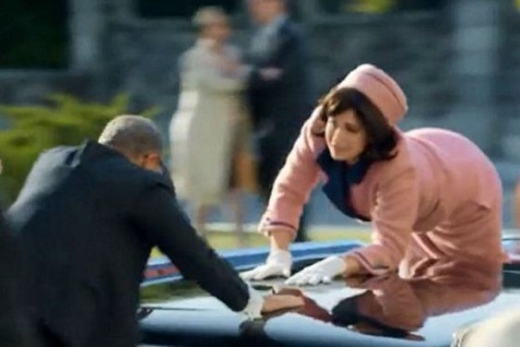 En el comercial se hace una apuesta entre policías y poco después se muestra a una mujer vestida como Jacqueline Kennedy pidiendo ayuda.