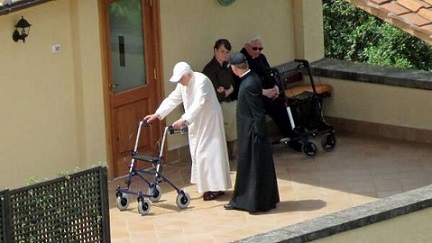 Benedicto XVI utiliza una gorra blanca para protegerse del sol. A su lado, el Arzobispo Georg Gänswein cuida del Sumo Pontífice Emérito.